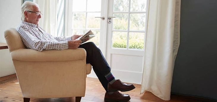 senior man reading newspaper in living room